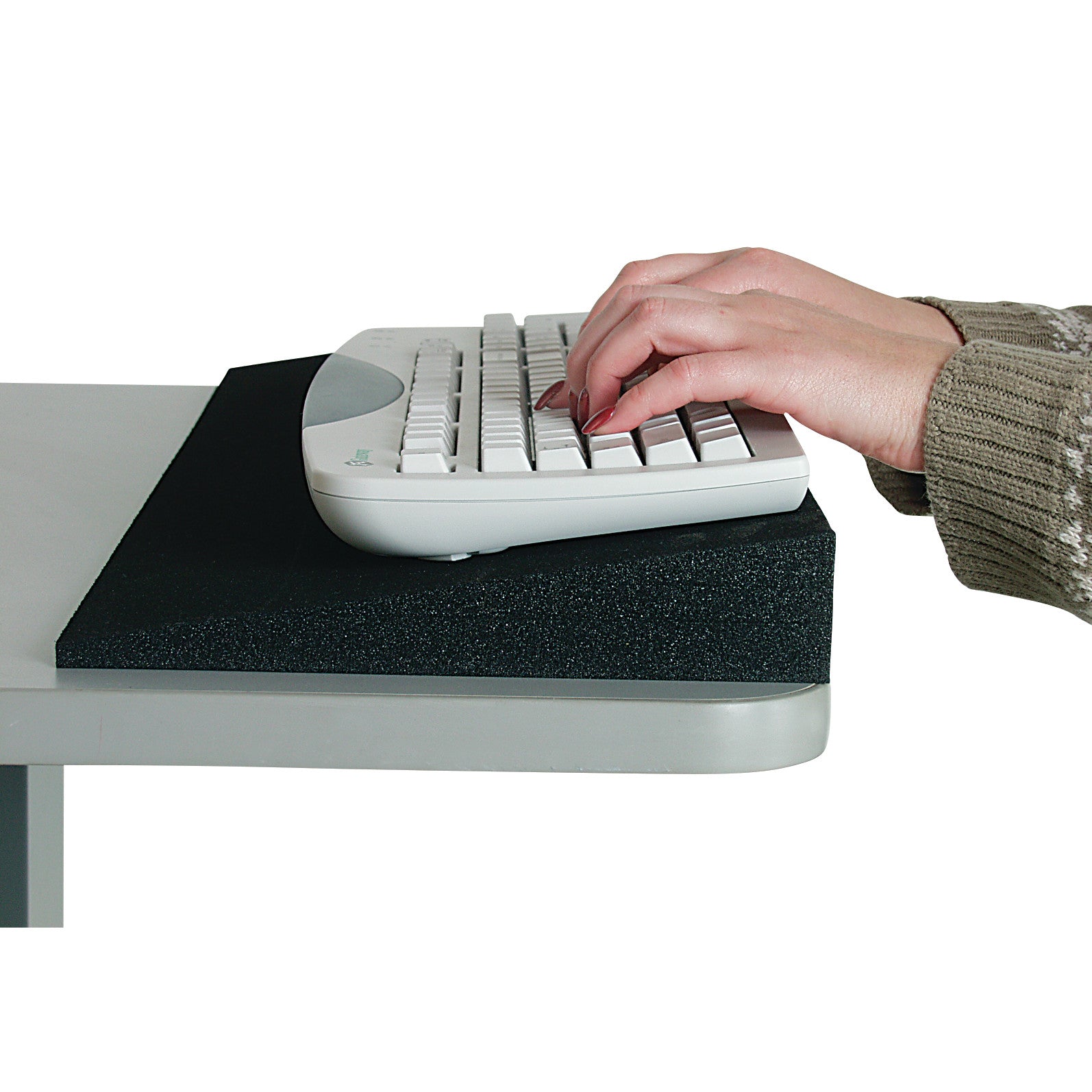 A person types on a keyboard placed on a black Desk Wedge, angled for ergonomic support, atop a desk.