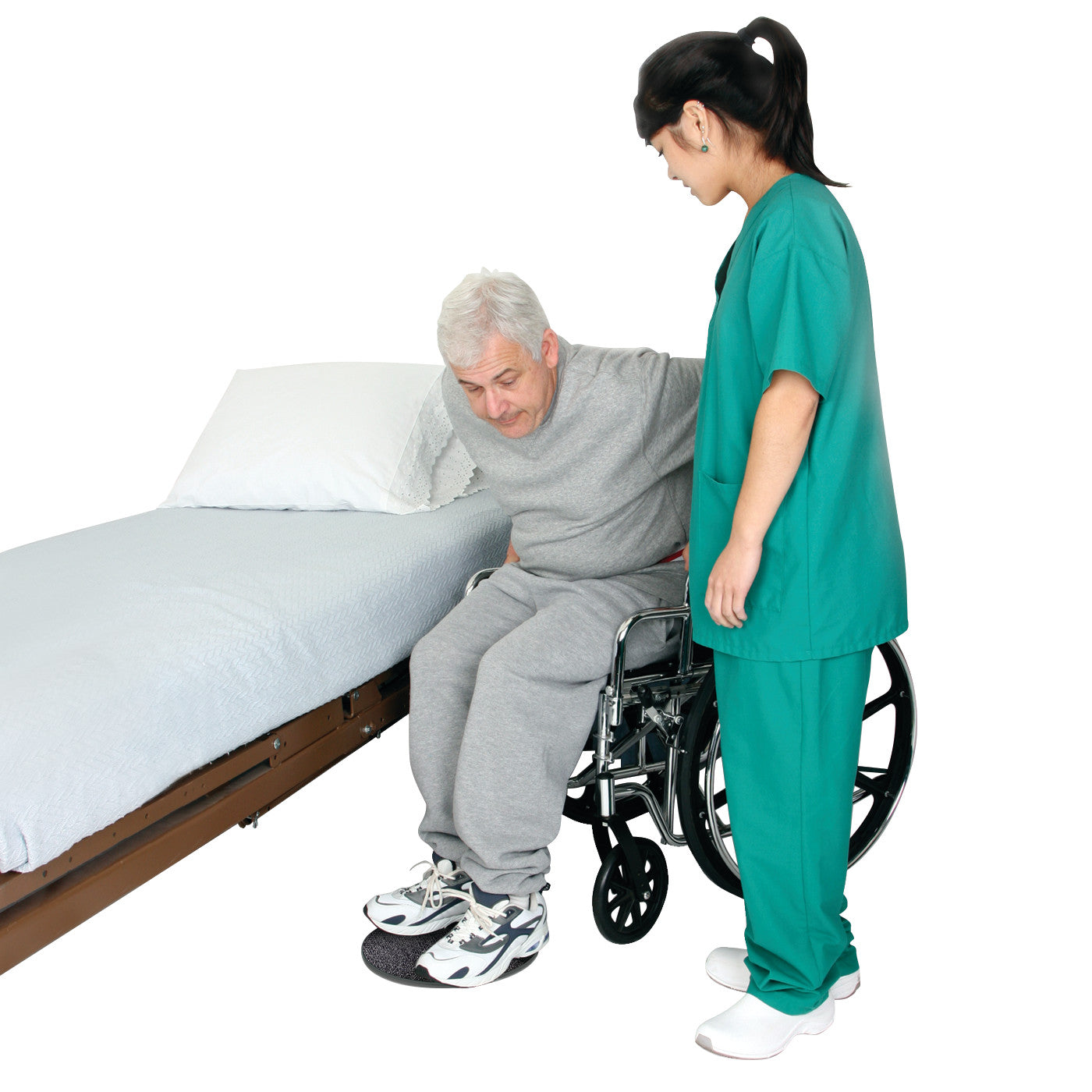 A caregiver helps a man transfer from a wheelchair to a bed using a SafetySure Pivot Disc on the floor for stability.