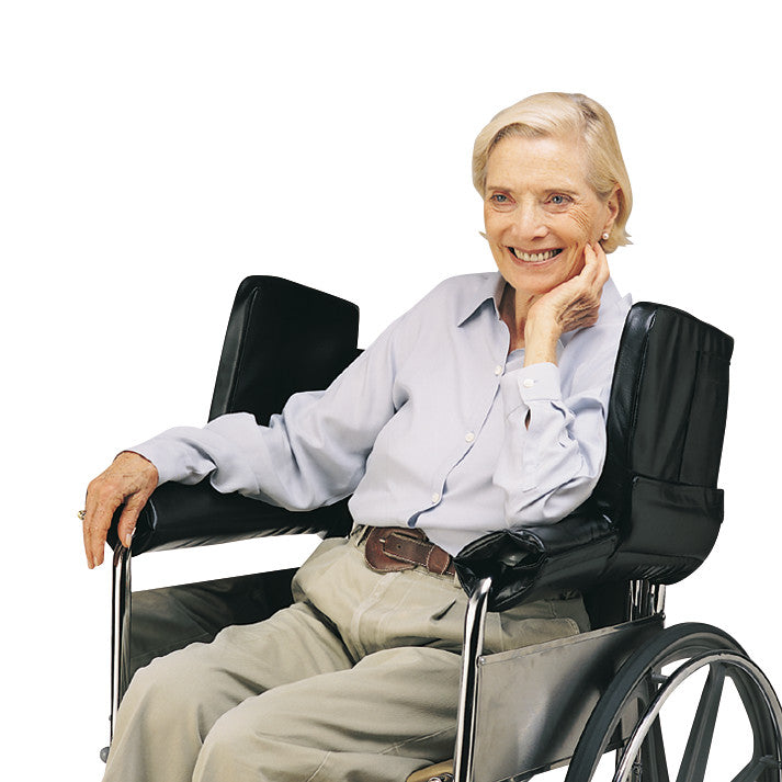 An elderly woman sits in a wheelchair with SkiL-Care Extra Support Wheelchair Side Wings, which provide added arm support.
