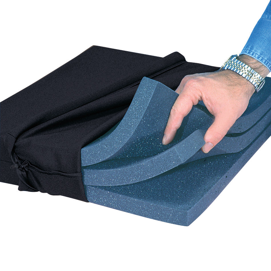 A hand adjusts layers of the AliMed High-Density Wheelchair Cushion, showing its blue foam interior and black fabric cover.