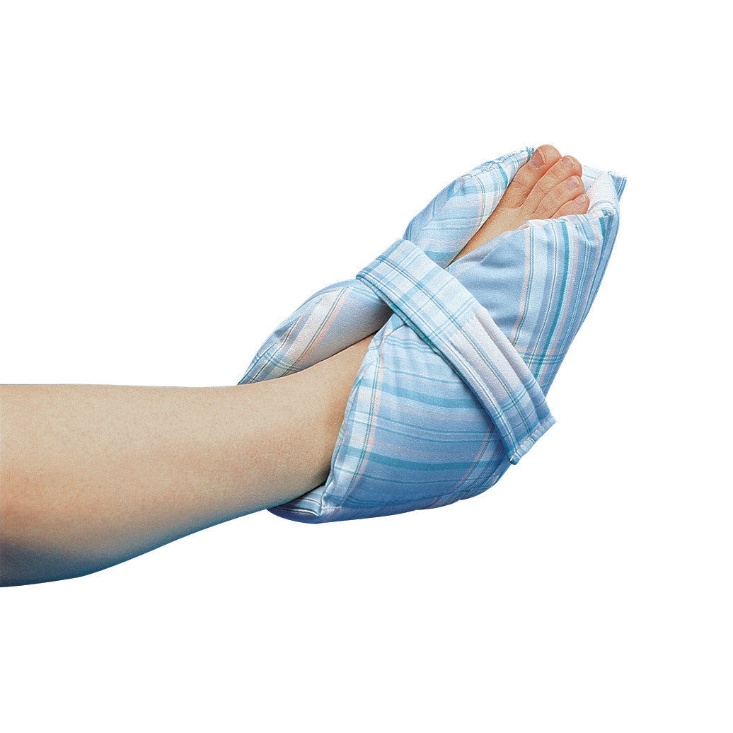 A foot is placed inside a Posey Heel Pillow, which is covered in a blue and white plaid fabric, with a strap securing it in place.