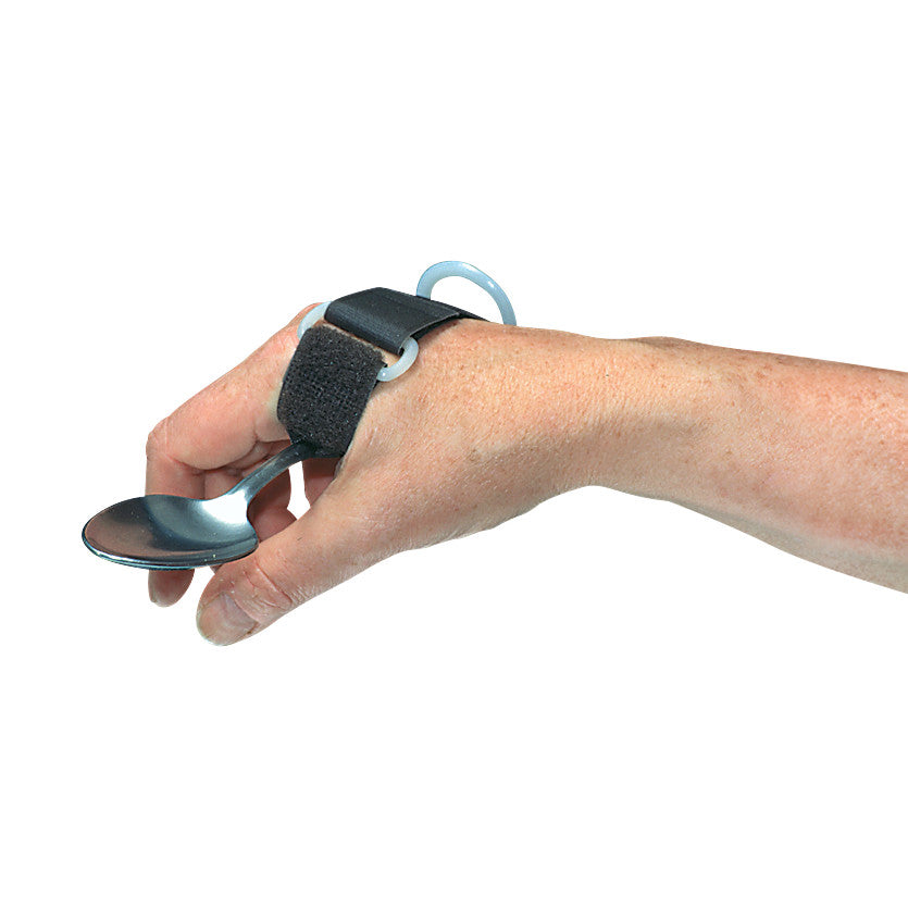 A hand wears a Therafin ADL Cuff With D-Ring, holding a spoon. The cuff is black with a strap and a D-ring for support.
