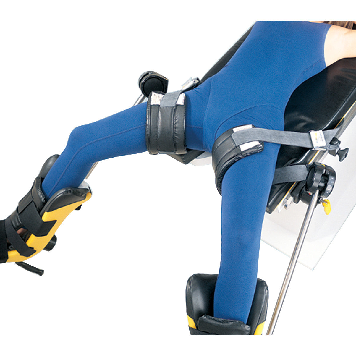A person wearing a blue outfit is secured on a medical table with Allen Nissen Strap restraints on the waist and legs.