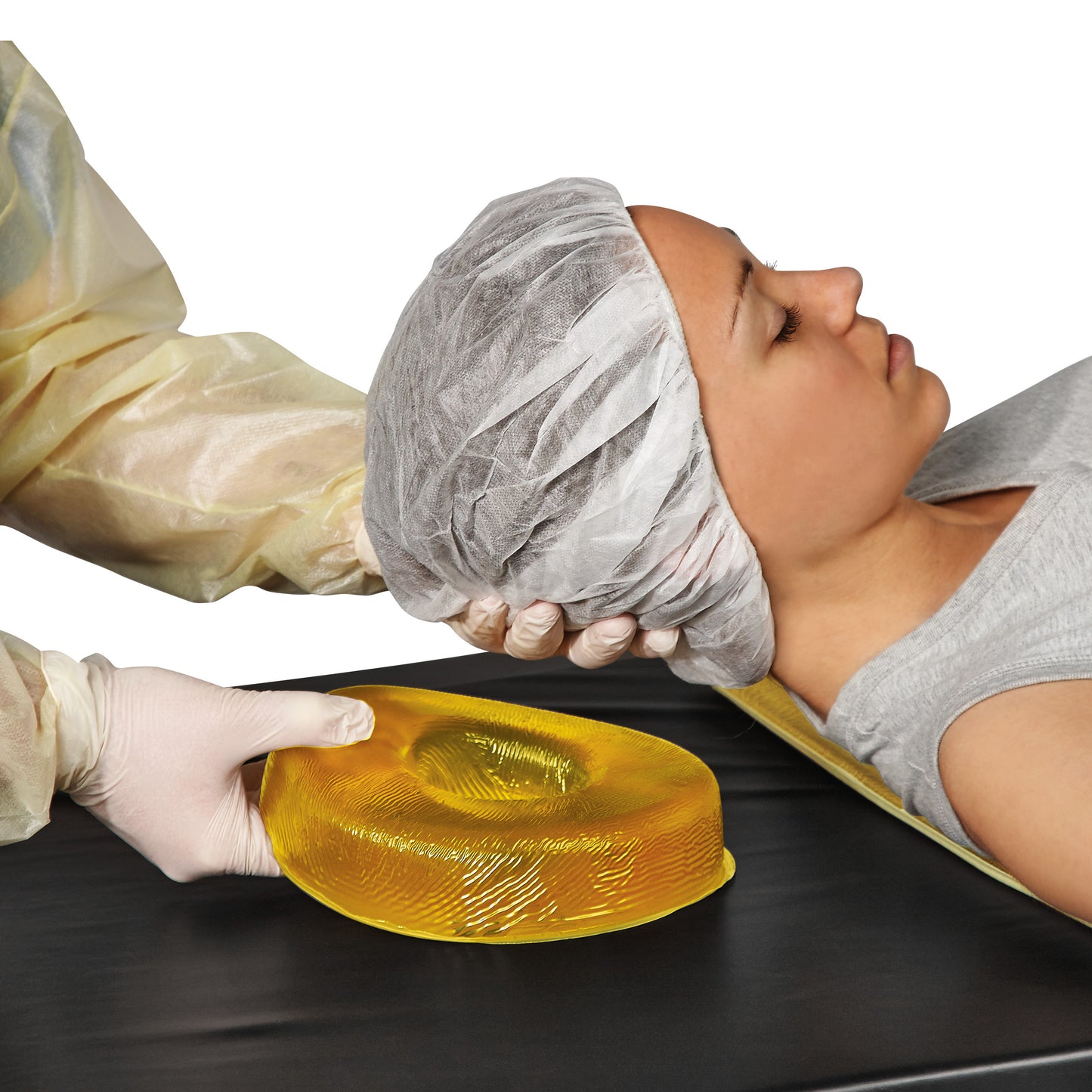 A person reclines as a caregiver positions an AliMed AliGel Head Donut under their head for support.