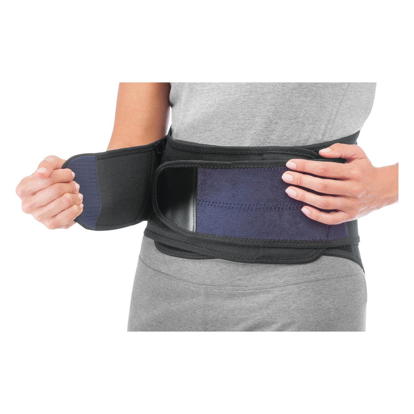 A person adjusts the Mueller Adjustable Back Brace around their waist, showing its black and blue design and strap closure.
