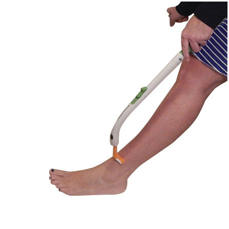 A person uses a FreedomWand, a long-handled tool, to shave their lower leg, demonstrating its functionality and reach.