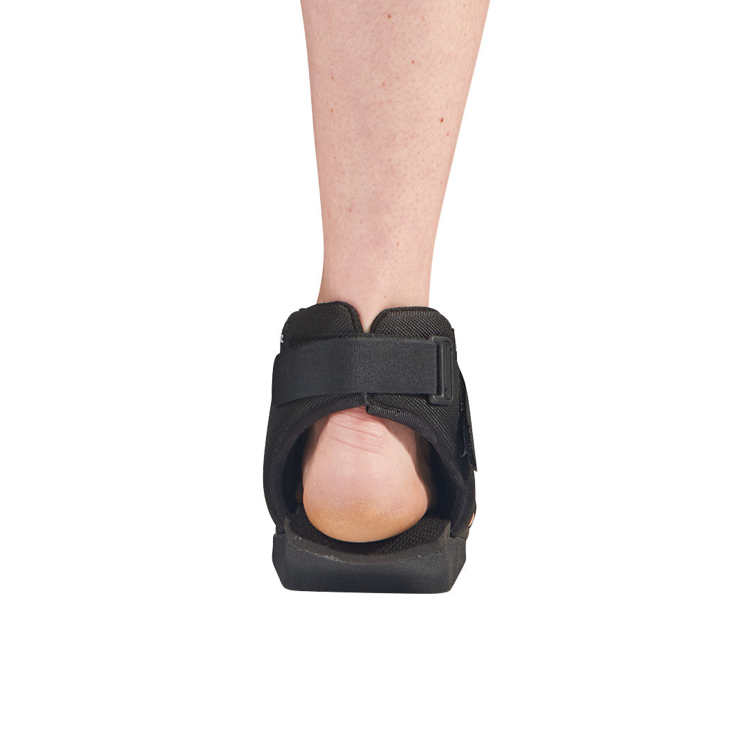 A person wearing the AliMed Open Heel Orthosis, viewed from the back. The orthosis is black with straps and an open heel design.