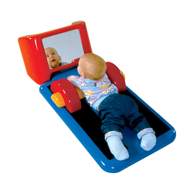 A baby lies on the Tumble Forms2 Tadpole Pediatric Positioner, featuring a blue mat with red supports and a mirror.