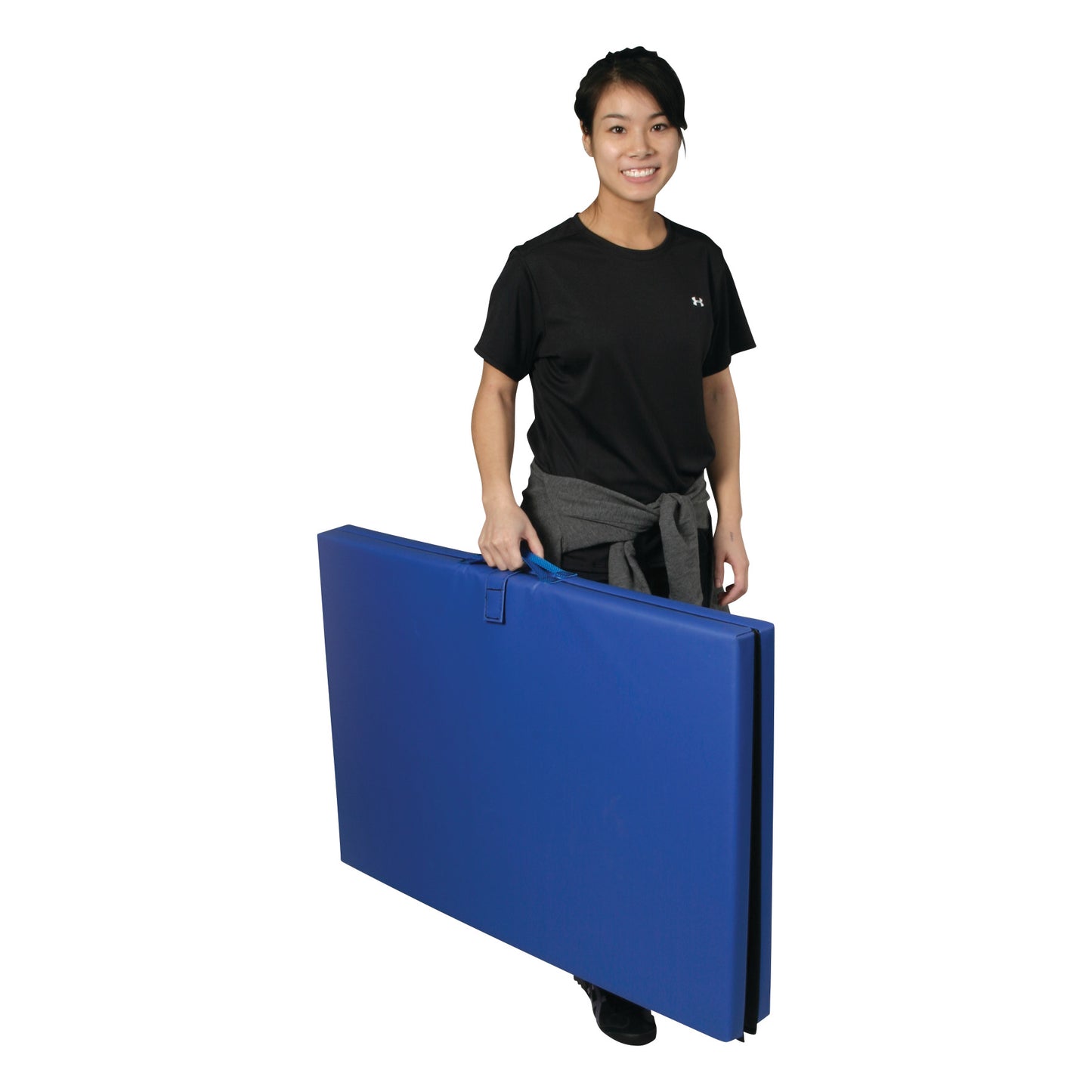 A person holding a folded AliMed Exercise Mat in blue, wearing a black T-shirt and gray pants. The mat has a handle on top.