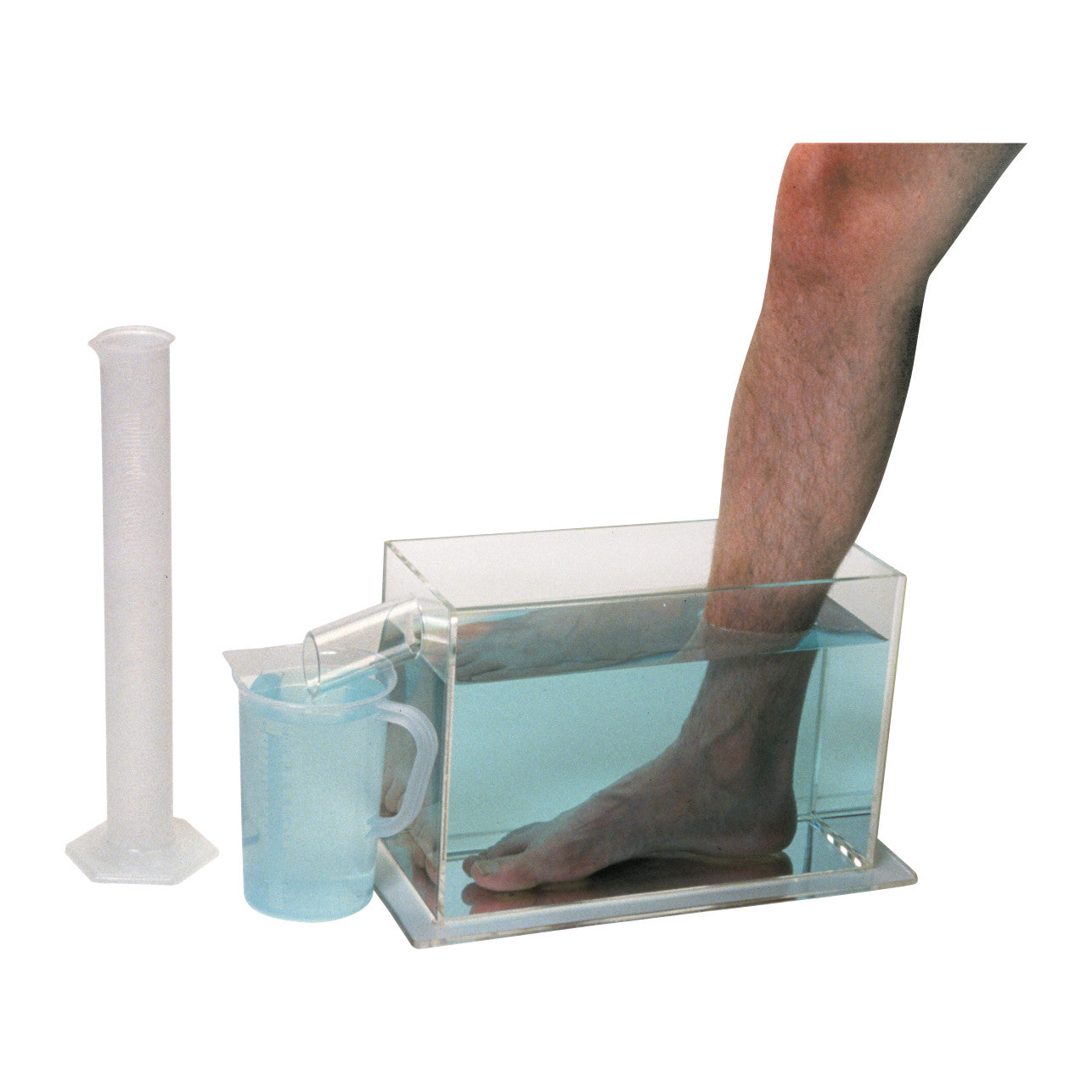 A foot submerged in a water-filled container from the Baseline Volumeter Set, with a measuring cup collecting overflow.