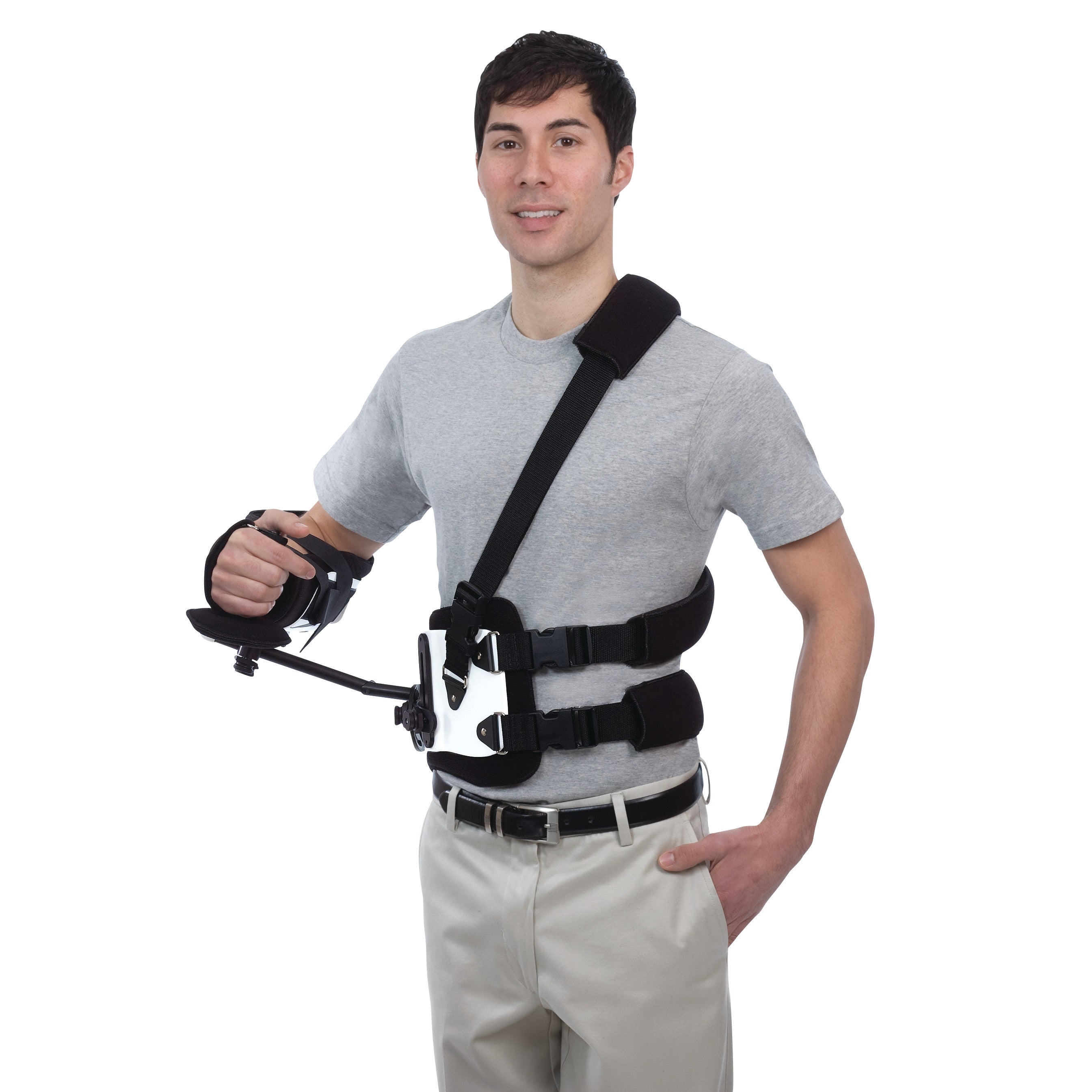 A person wears the Trulife Gunslinger II orthosis, a shoulder and arm brace with straps, over a gray shirt and khaki pants.