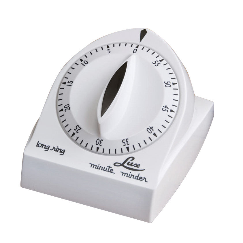 A white Lux minute minder bell timer with a black dial marked from 0 to 60 minutes, labeled "long ring" and "Lux minute minder."