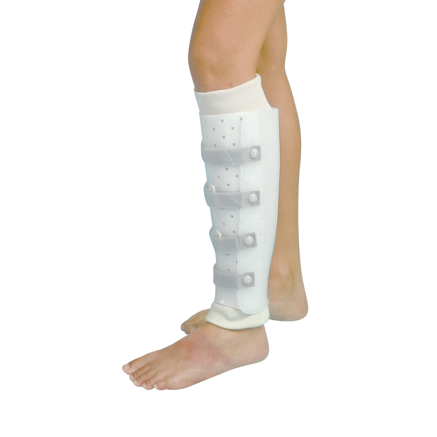 A person wears a Miami Prefabricated Tibial Fracture Brace on their left leg. The white brace has straps and covers the lower leg.