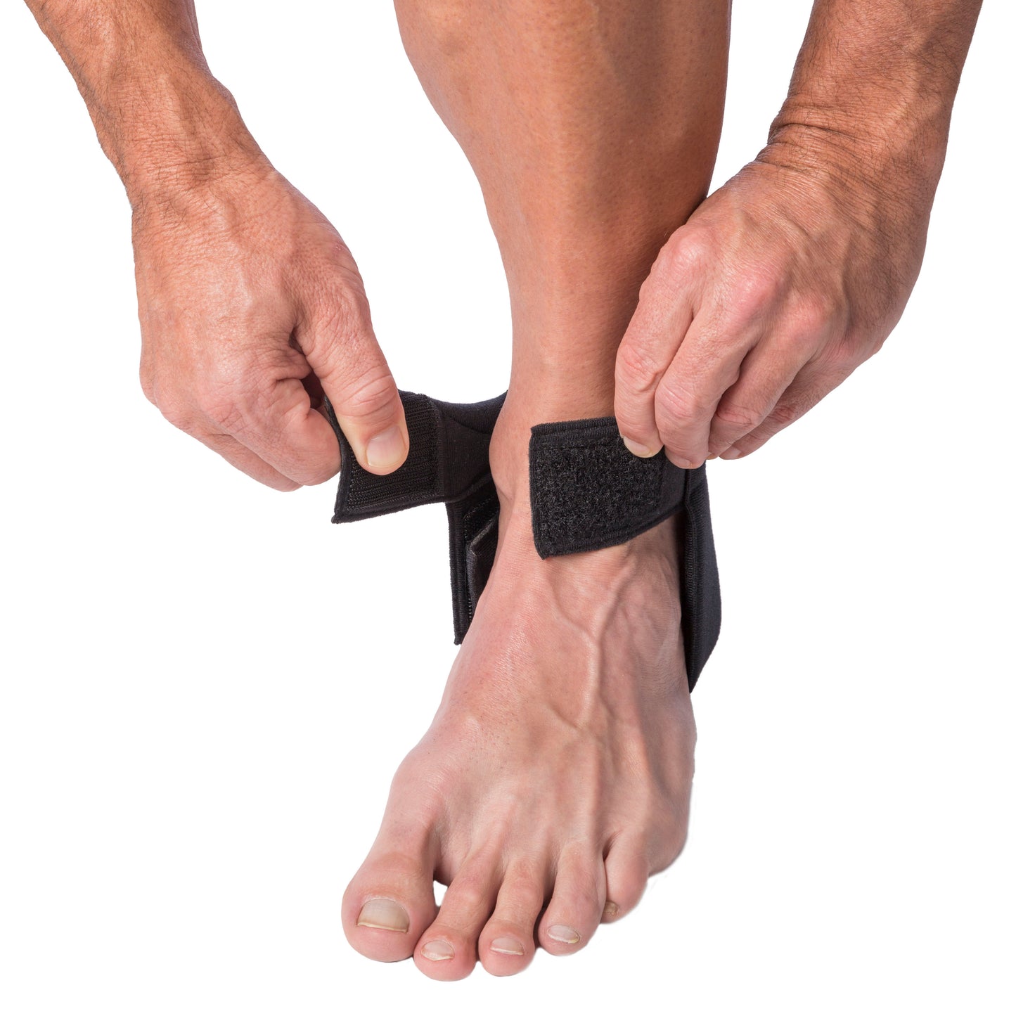 A person fastens the Cho-Pat Achilles Tendon Strap around their ankle. The black strap provides support to the Achilles tendon.