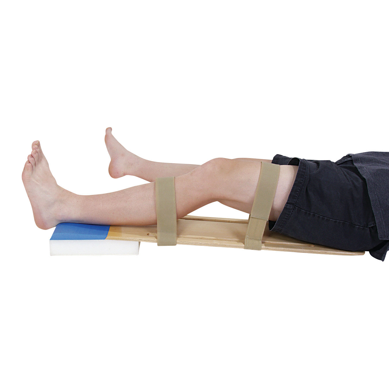 A person using the AliMed KneeCrank II Knee Extension Orthosis. The leg is strapped to a wooden board with padding under the heel.