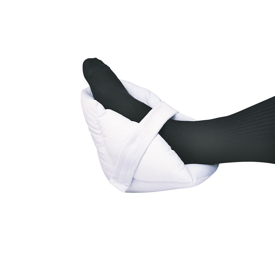 Foot in a SkiL-Care Ultrasoft Heel Cushion with black socks. The white cushion wraps around the heel for comfort and protection.