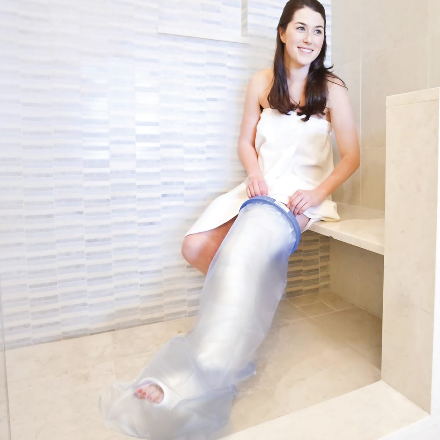 A woman sits in a shower, using the Brownmed SEAL-TIGHT Original Cast and Bandage Protector to cover her right leg.