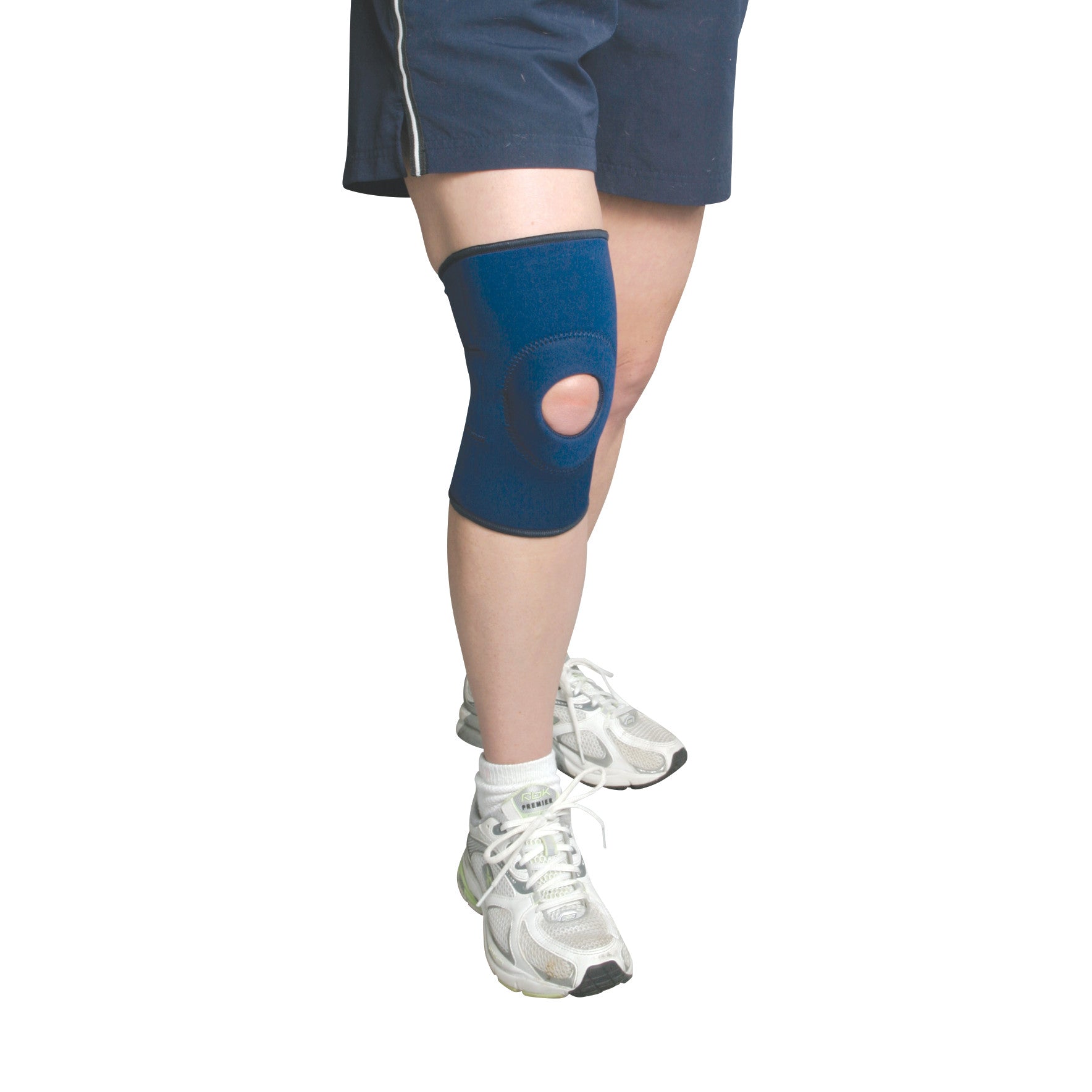 A person wearing the AliMed Knee Support with Open Patella, shown in blue, paired with shorts and white sneakers.