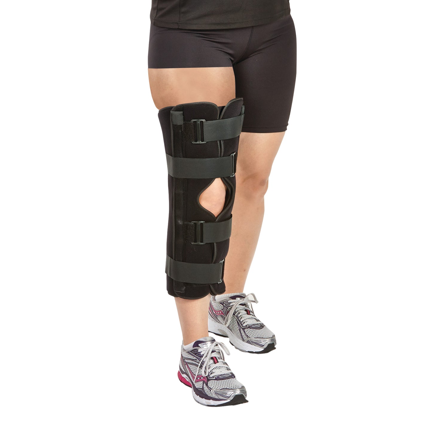 A person wears an AliMed FREEDOM comfort Three-Panel Knee Immobilizer on the right leg, accompanied by athletic shoes and shorts.