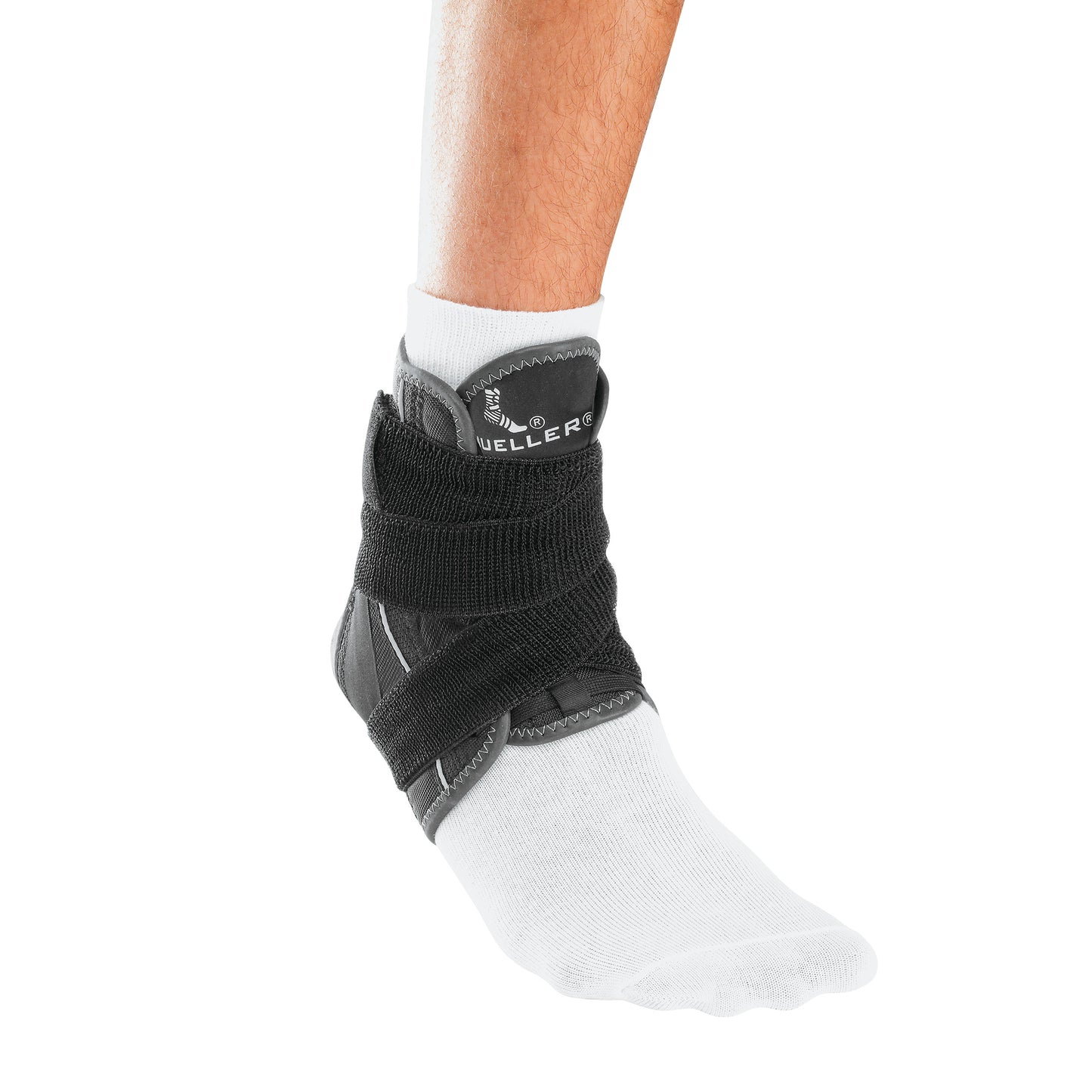 A person wears the Mueller Hg80 Ankle Brace with Straps over a white sock, providing support and stability to the ankle.