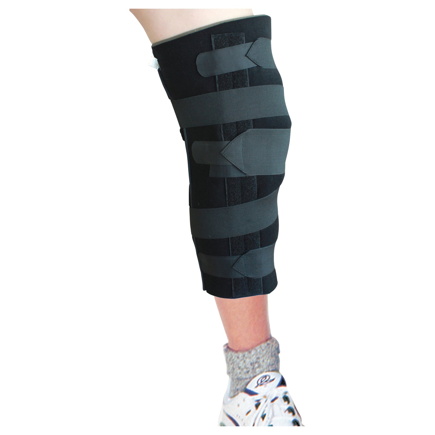 A leg wearing the AliMed Economy Foam Knee Immobilizer, featuring black foam and adjustable straps, over a grey sock and sneaker.