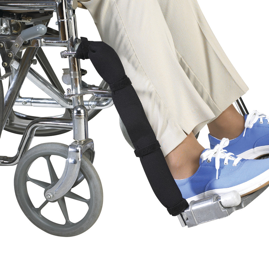 A person in a wheelchair uses the SkiL-Care Skin-Guard Leg Protector, a padded black strap securing the legs.