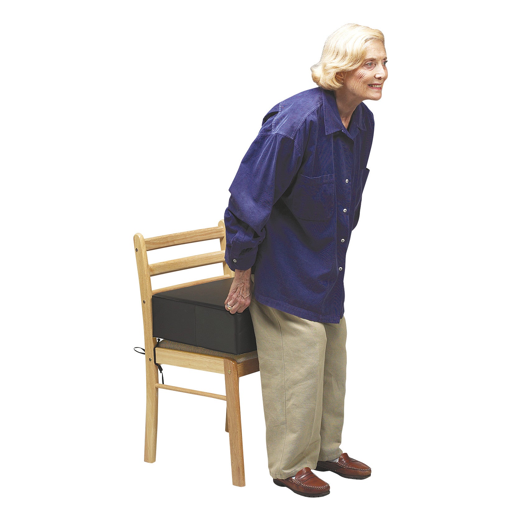 An older adult using the SkiL-Care Post-Hip Surgery Cushion on a wooden chair. The cushion provides elevated seating support.