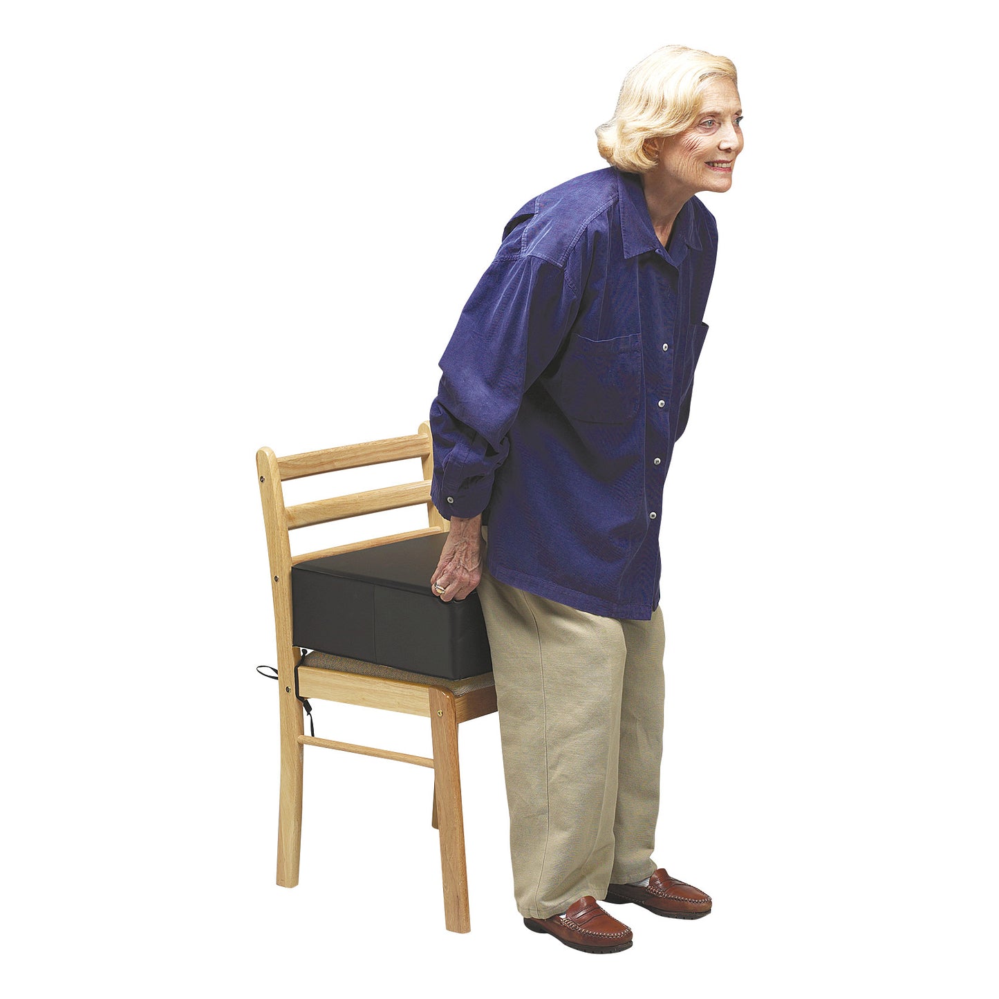 An older adult using the SkiL-Care Post-Hip Surgery Cushion on a wooden chair. The cushion provides elevated seating support.