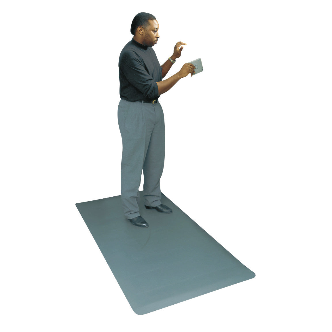 A person stands on a large, gray Wearwell ESD Anti-Fatigue Mat, reading a small tablet. The mat is designed to reduce fatigue.