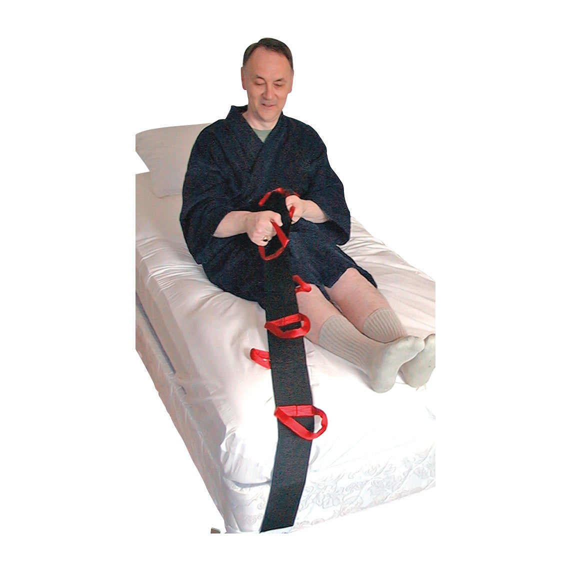 A person in a robe uses the SafetySure Bed Pull-Up, a black and red strap with handles, to assist in sitting up on a bed.