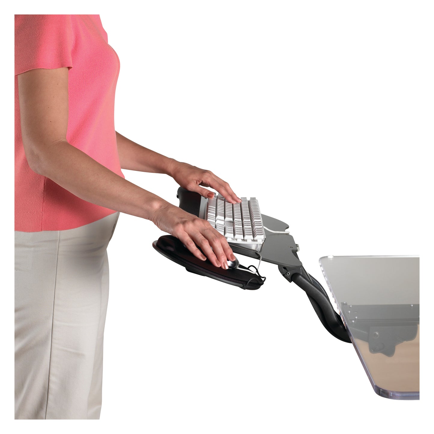 A woman uses the Weber Knapp Cobra Sit-to-Stand Keyboard Tray, adjusting its position while typing on a keyboard.