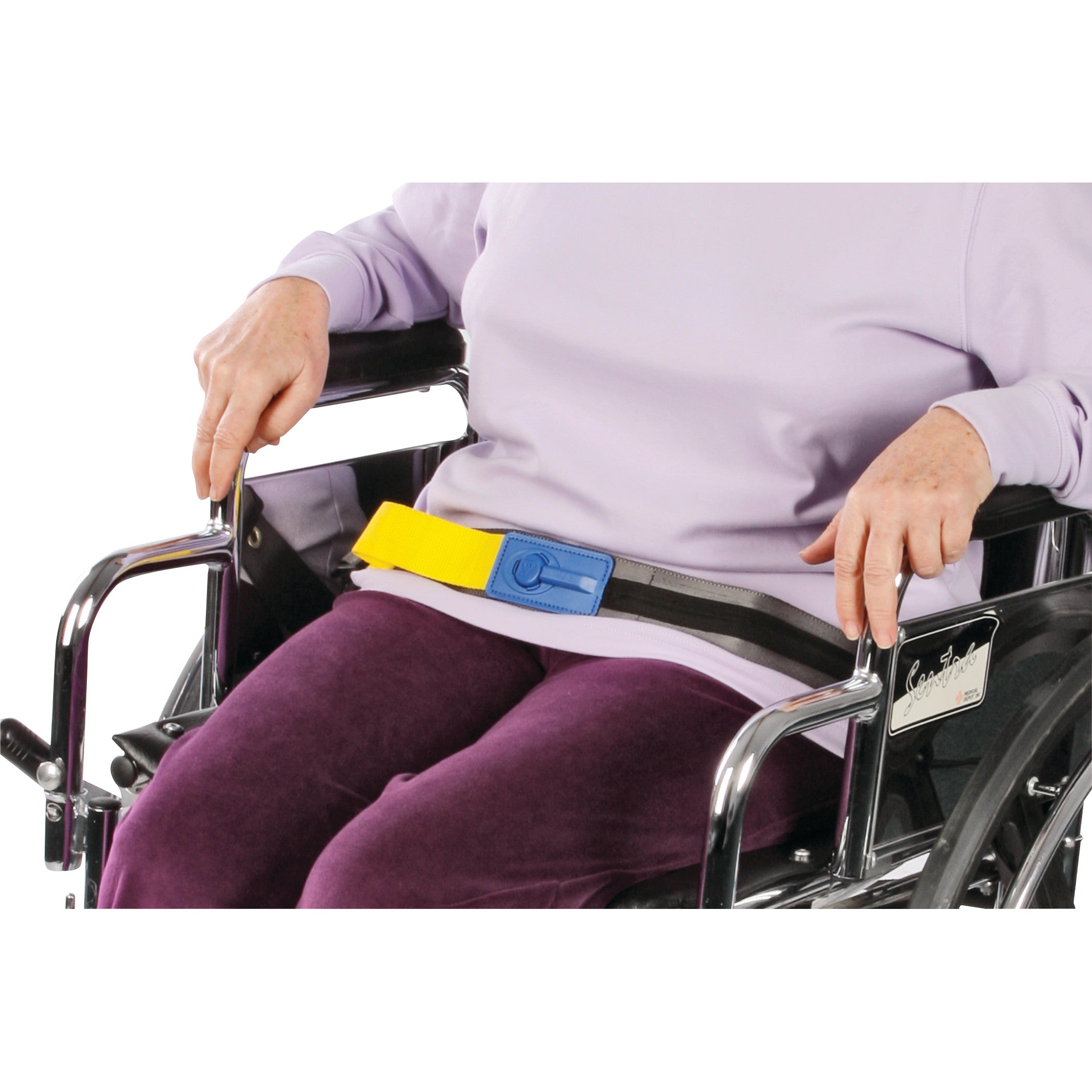 A person in a wheelchair wears an AliMed Early Warning E-Z Release Seatbelt with a yellow strap and blue buckle.