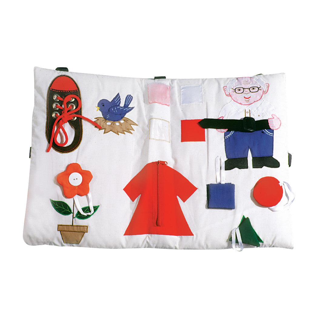 An Activity Pillow with various elements like a shoe to lace, bird, flower, red dress, and figure with a belt, for sensory engagement.