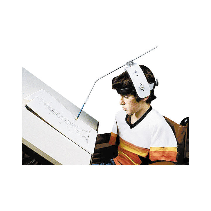A child wearing an Adjustable Head Pointer to draw on paper, using a head-mounted tool for accessibility, sits at a tilted table.