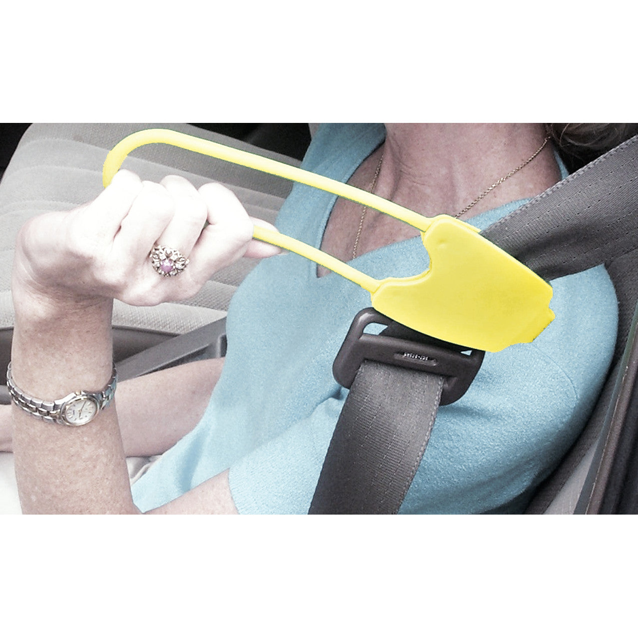 A person uses the Easy Reach Seat Belt Handle, a yellow tool, to pull a car seat belt forward for easier access.