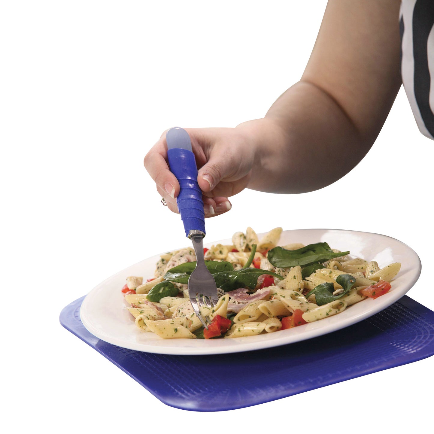 A person holds a fork with a large handle, eating pasta on a plate. The plate rests on a Dycem Nonslip Rectangular Matting.
