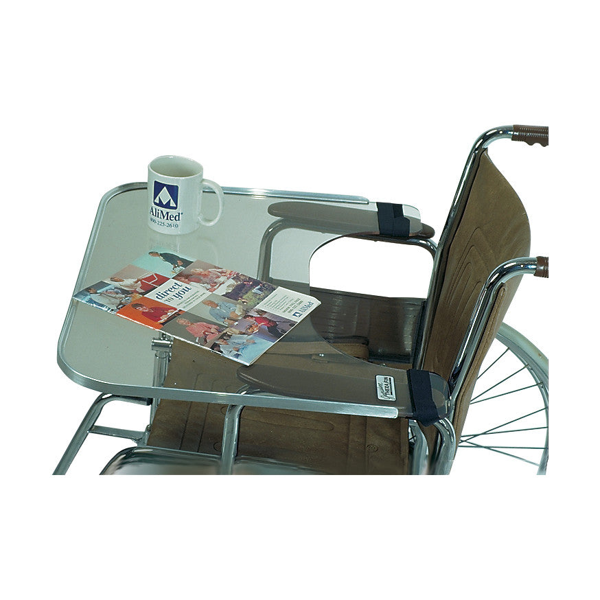 A wheelchair with a Therafin Transparent Lap Tray, featuring a magazine and mug on its surface.