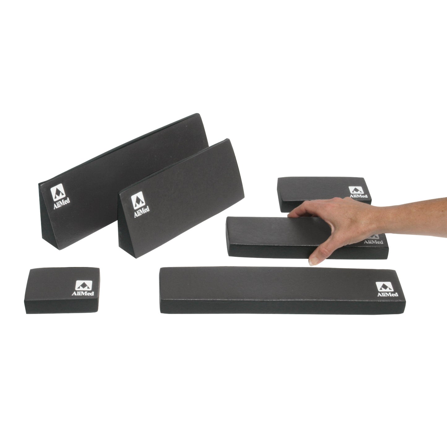 A hand reaches for a piece from the black AliMed MRI Immobilization Set, which includes various foam blocks of different sizes.