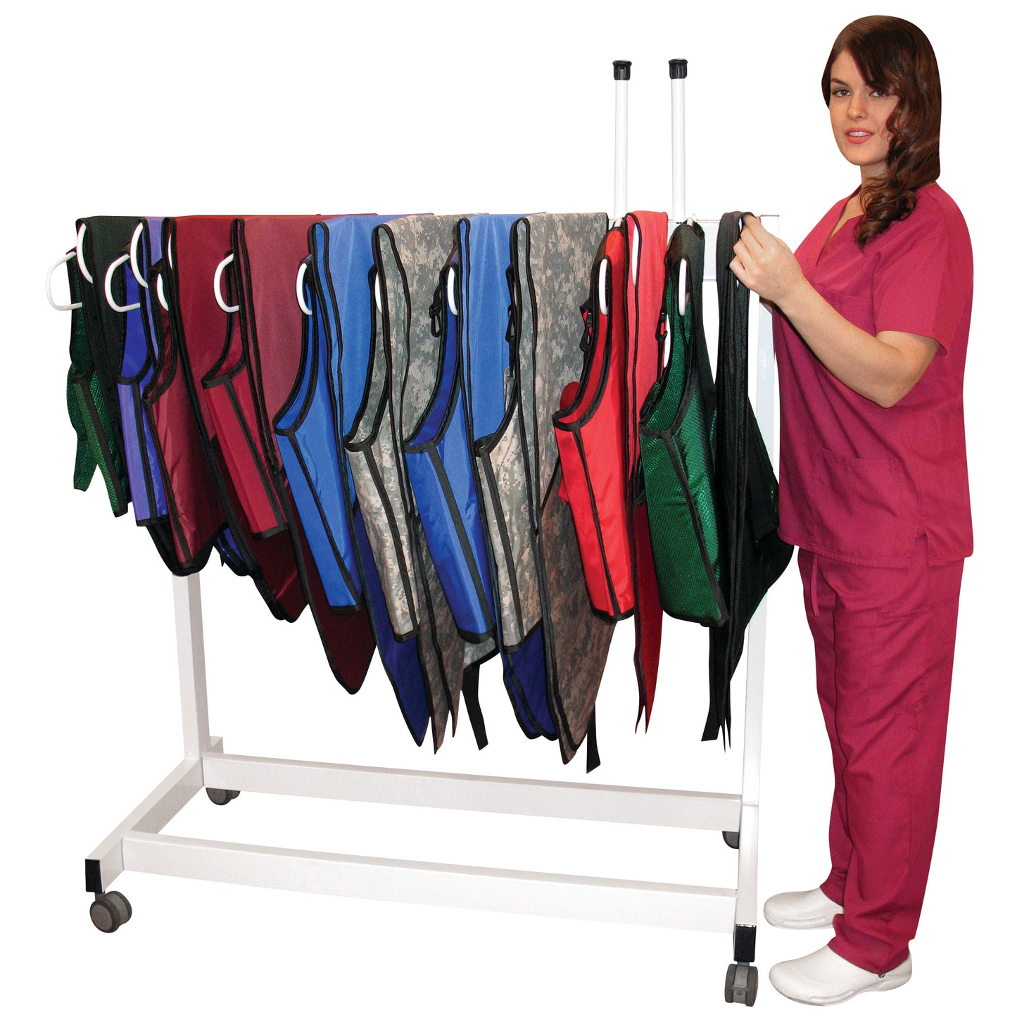 A person in pink scrubs stands next to the Deca-Rack Vest and Kilt Rack holding colorful vests. The rack is on wheels.