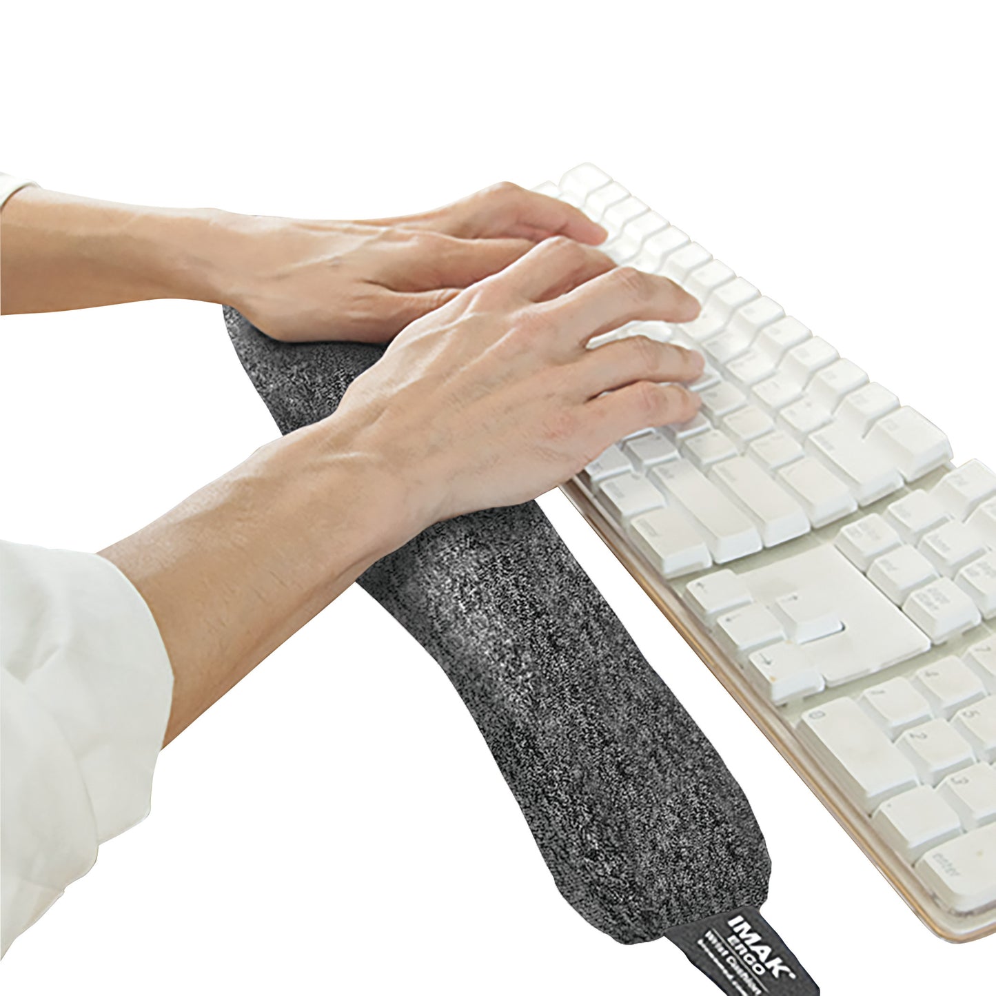 Hands rest on a Brownmed IMAK ergoBeads Keyboard Mouse Cushion, placed in front of a white keyboard for ergonomic support.