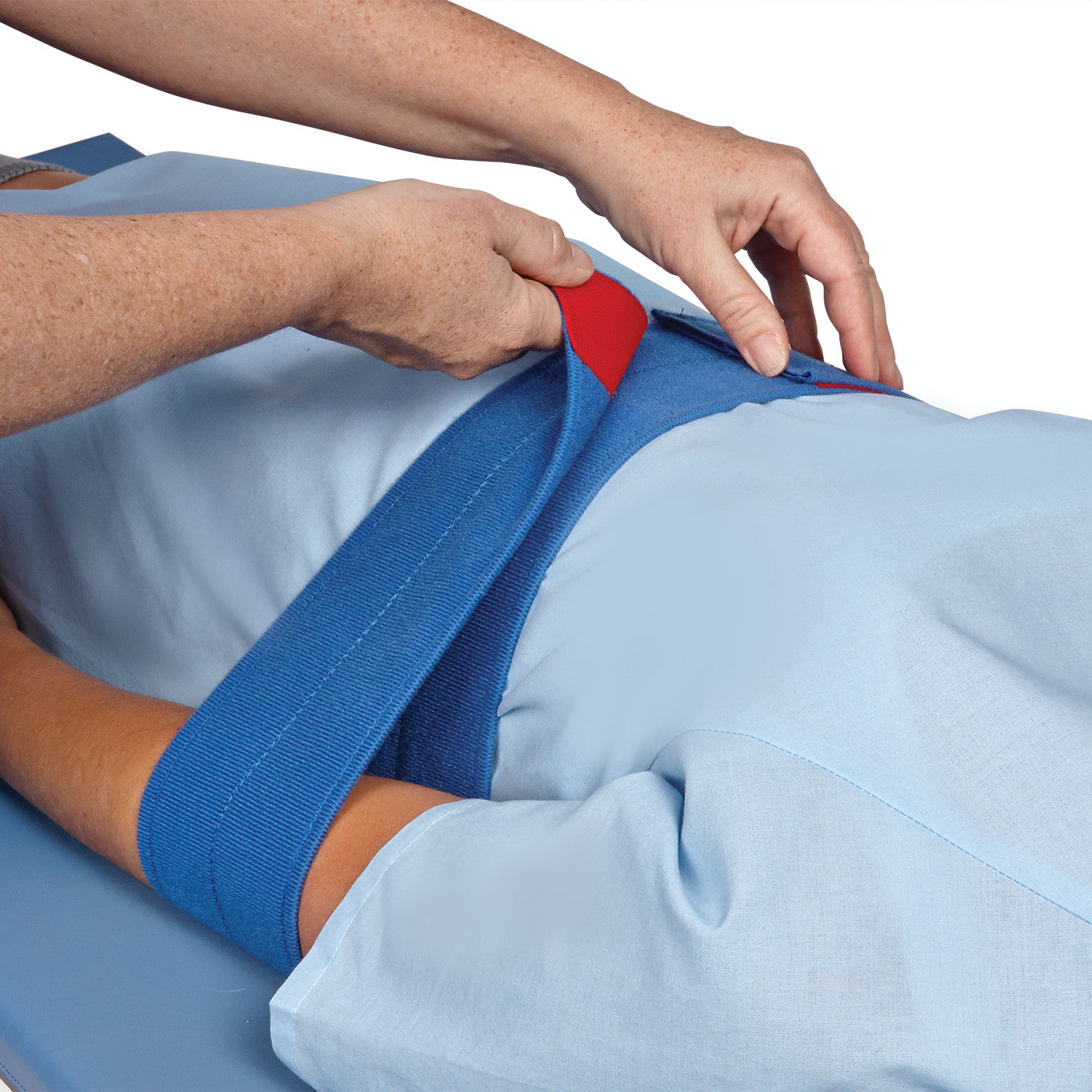 Person secures a patient's arm with the AliMed MRI/CT Arm Holder, featuring a blue strap with a red fastening area.