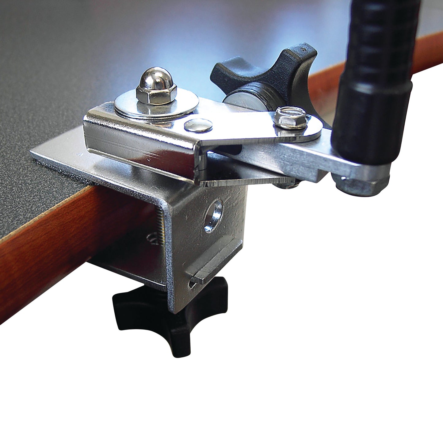 The Tab Grabber, a silver metal clamp tool, securing a tablet to a table edge with adjustable knobs for tightening.