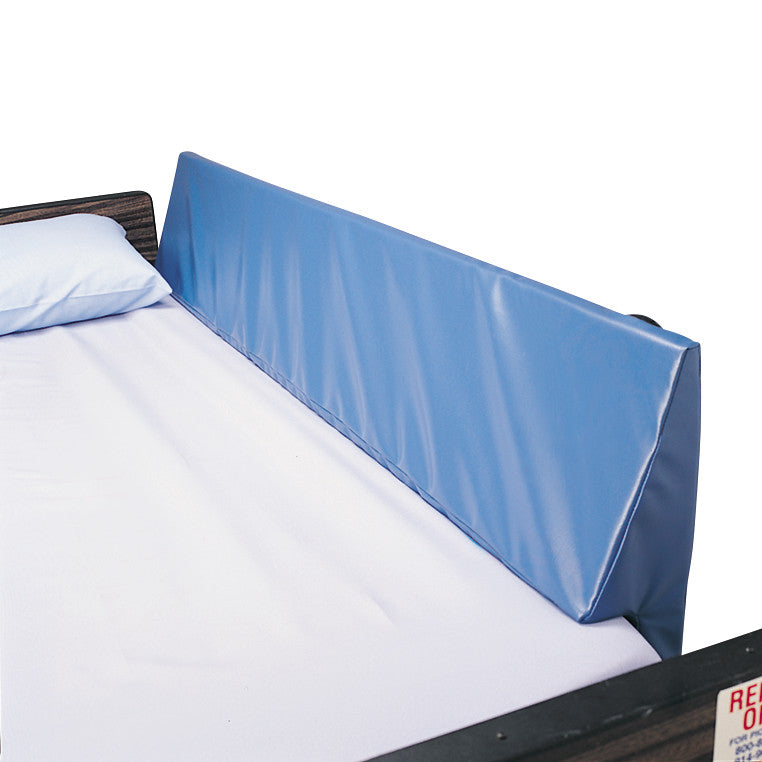 A bed features a SkiL-Care Bed Rail Wedge Pad in blue, placed against the side rail, with a white sheet and pillow.