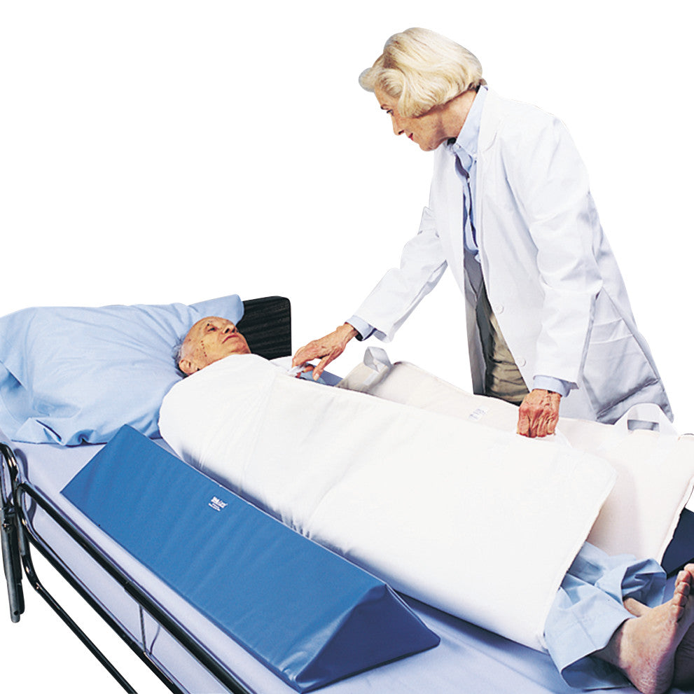 An elderly patient lies in bed with a healthcare worker adjusting a Replacement Pad for SkiL-Care In-Bed Patient Positioning System.