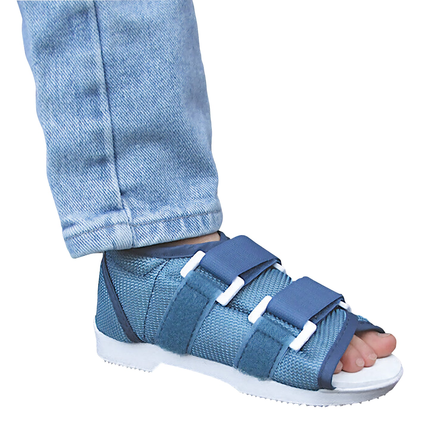 A child's foot wearing the DARCO Original Pediatric MedSurg Shoe, with blue straps and a white sole, over light blue jeans.