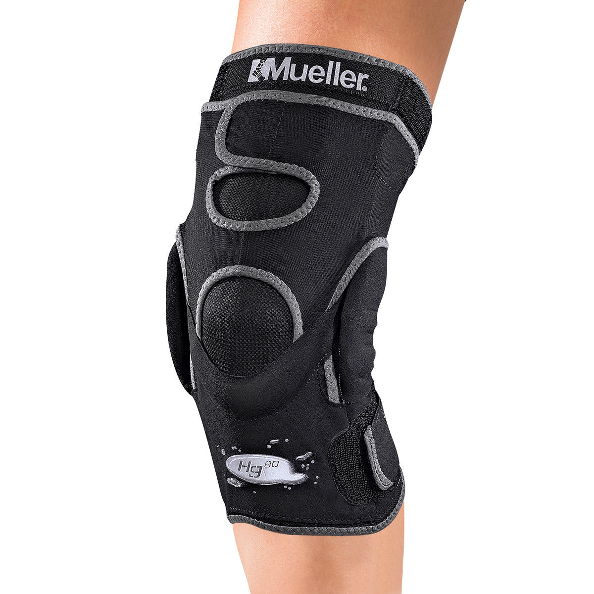 A person wearing a Mueller Hg80 Knee Brace, featuring a black design with gray accents and cut-out sections for flexibility.