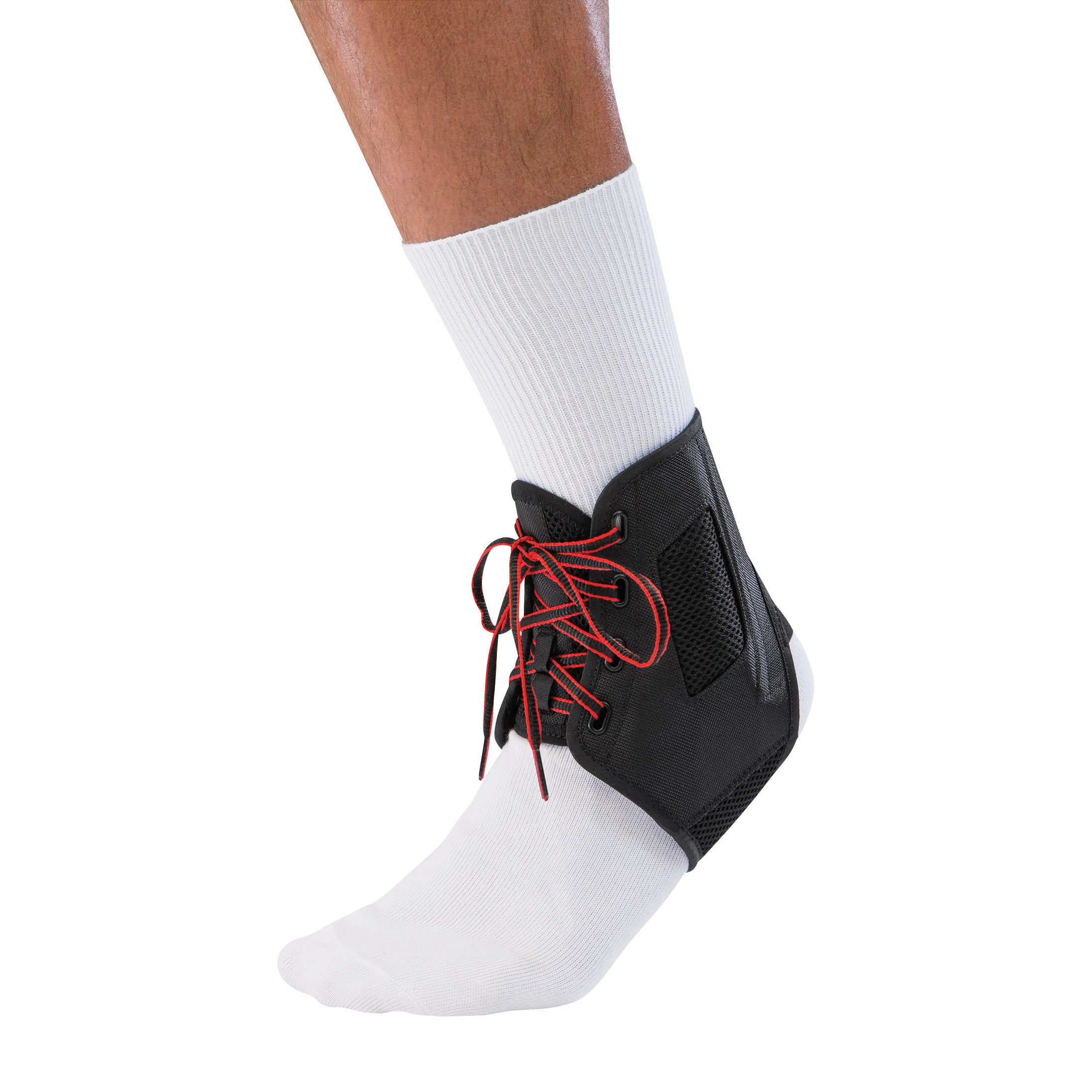 A person wears a Mueller ATF 3 Ankle Brace over a white sock. The brace is black with red laces providing support to the ankle.