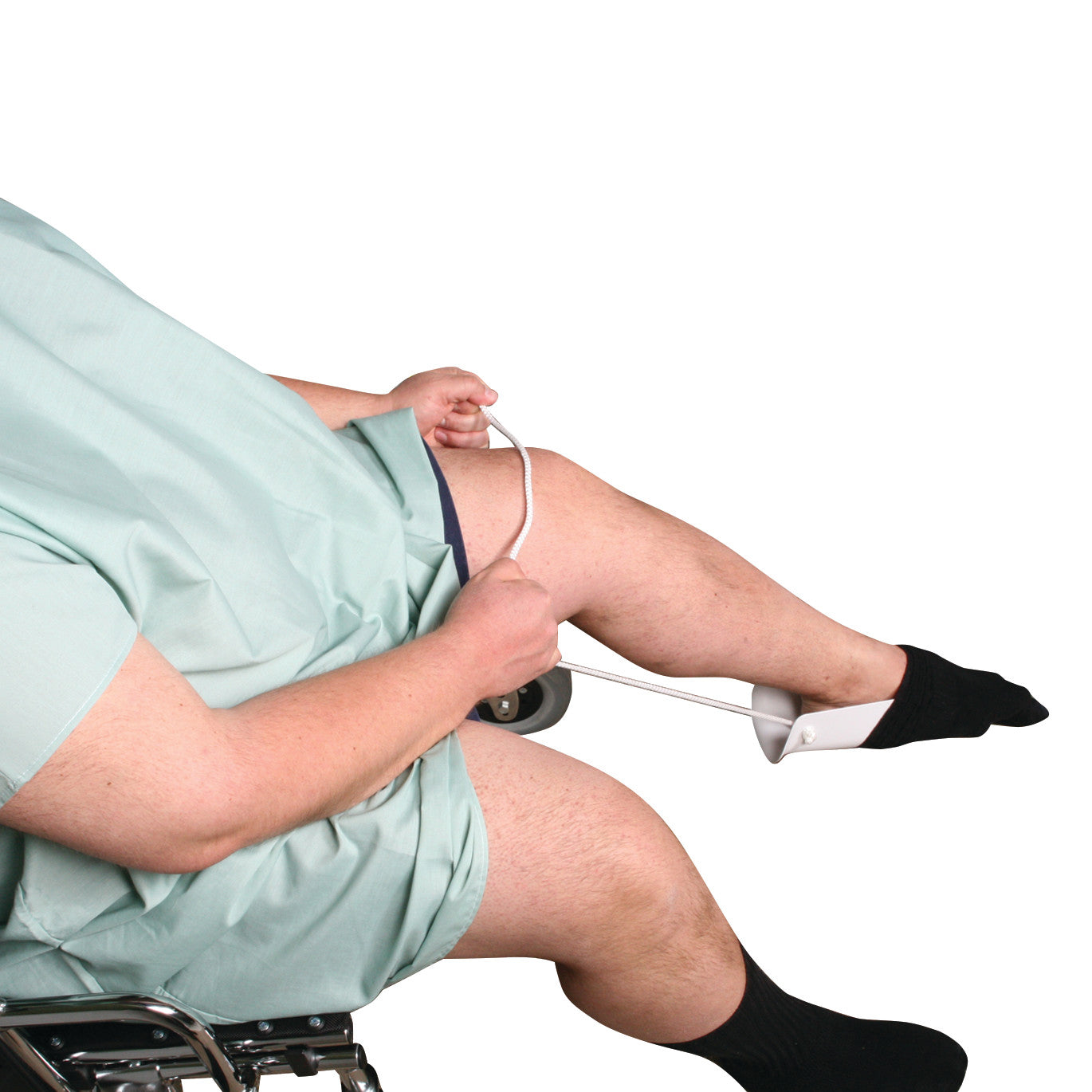 A person in a hospital gown uses the AliMed Extra-Wide Single-Cord Sock Aid to put on a sock while sitting in a wheelchair.