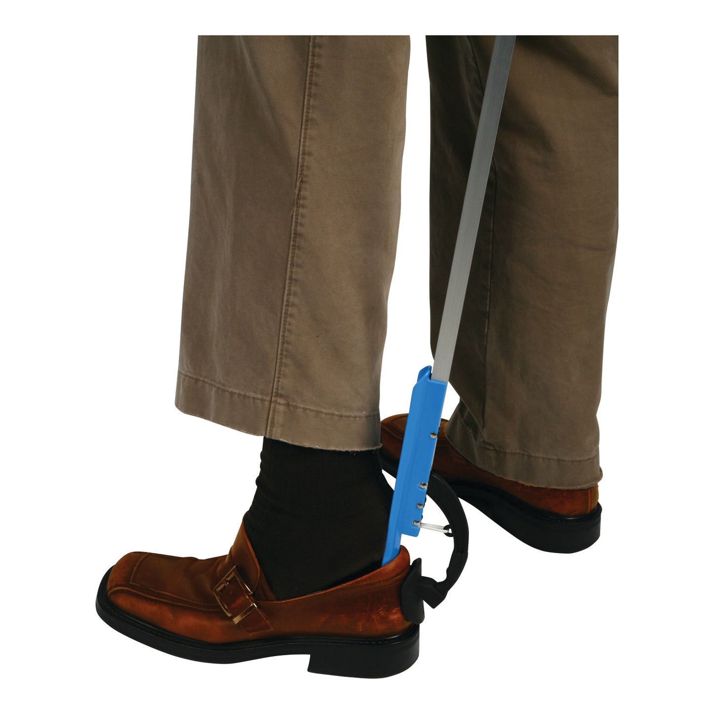 A person uses a Shoehorn Reacher, a long device with a blue handle, to assist in putting on brown shoes, wearing tan pants.