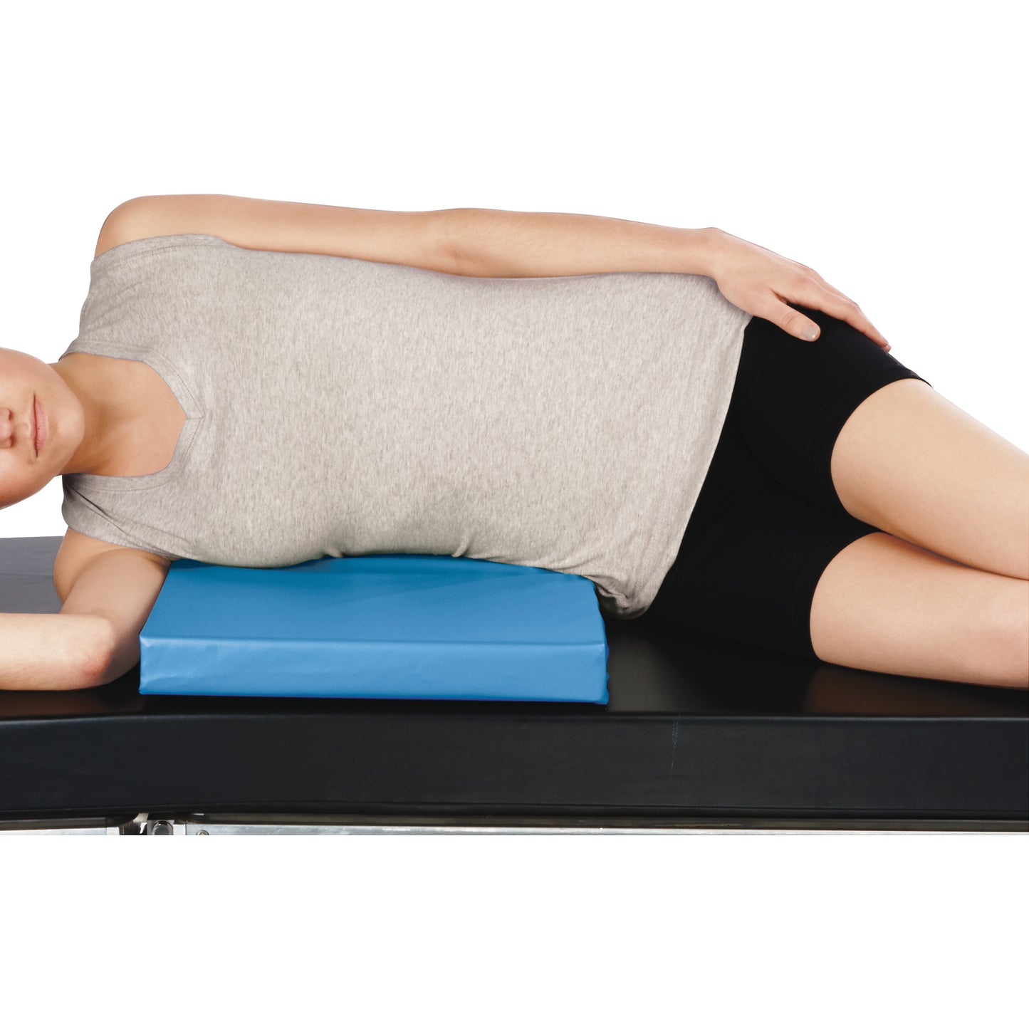 A person lies sideways on a black surface using the AliMed Vinyl-Covered Decubitus Abdominal Pad for support.